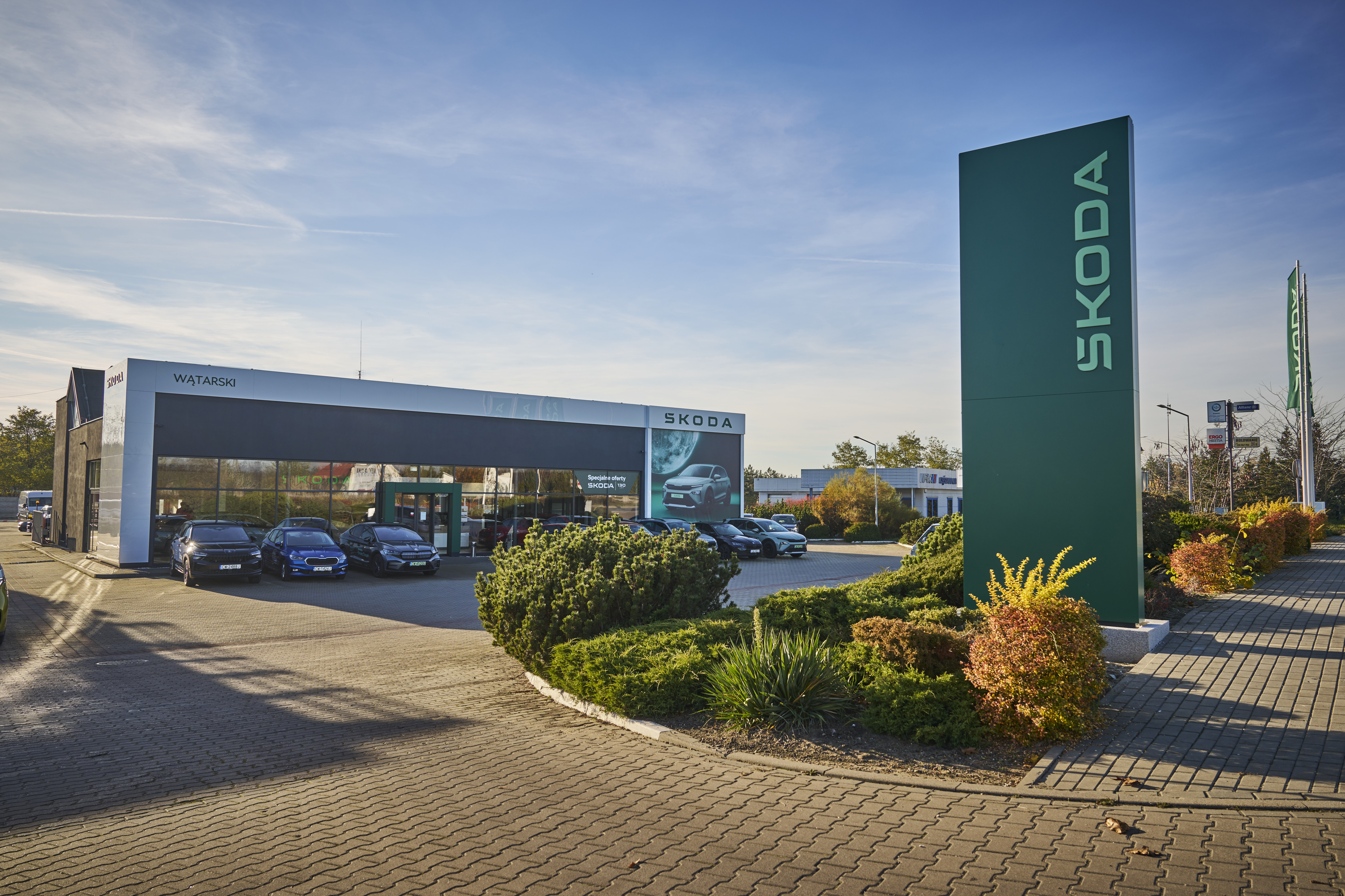 Škoda cars are lined up in front of the modern building as well as inside it.